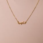 A 'Maktub' raised calligraphy necklace in 18k gold-plated sterling silver, showing the 3D effect of the Arabic script on the round medallion.