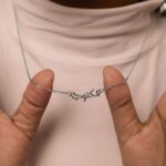 A 'Maktub' raised calligraphy necklace in 18k gold-plated sterling silver, showing the 3D effect of the Arabic script on the round medallion.