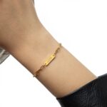 'Ukhti' Arabic calligraphy sister link bracelet in 18k gold-plated sterling silver, shown on a woman's wrist.