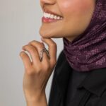 A woman's hand wearing the Kinetic Orbiting Sphere Ring in 18k gold-plated sterling silver, showing the moving bead on the elegant double band.