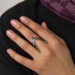A woman's hand wearing the Kinetic Orbiting Sphere Ring in 18k gold-plated sterling silver, showing the moving bead on the elegant double band.