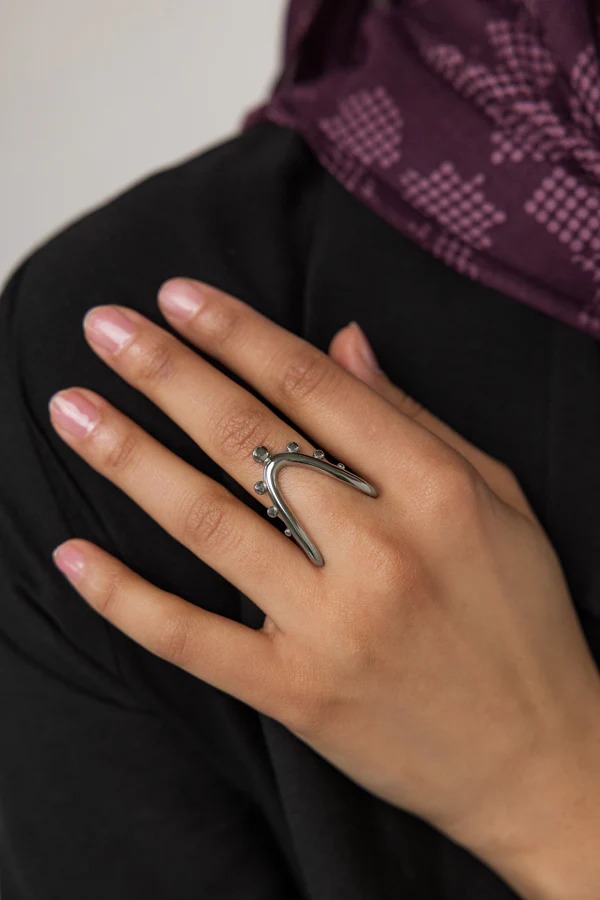 A woman's hand wearing the Kinetic Orbiting Sphere Ring in 18k gold-plated sterling silver, showing the moving bead on the elegant double band.