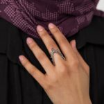 A woman's hand wearing the Kinetic Orbiting Sphere Ring in 18k gold-plated sterling silver, showing the moving bead on the elegant double band.