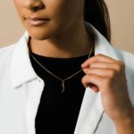 A floating Arabic initial 'S' (Seen) necklace in 18k gold-plated sterling silver, showing the unique sideways design of the letter integrated into the chain.