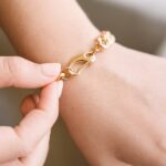 A woman's wrist wearing the bold Cuban link bracelet in 18k gold-plated sterling silver, showing the chunky, interlocking design.