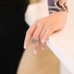 A delicate Olive Branch Peace Ring in 18k gold-plated sterling silver, worn on a finger to showcase the leaf design wrapping around it.