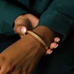 A wide Ayatul Kursi cuff bracelet in 18k rose gold-plated sterling silver, showing the intricate Arabic engraving of The Throne Verse on a woman's wrist.