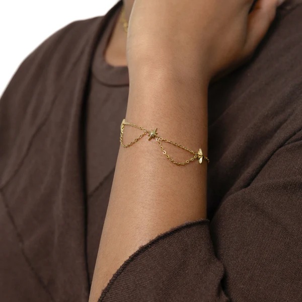 Guiding North Star Charm Bracelet in 18k gold-plated sterling silver, worn on a woman's wrist, highlighting the delicate starburst charms.