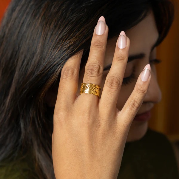 'Yusr' (Ease) Arabic calligraphy signet ring in 18k gold-plated sterling silver, worn on a finger to showcase the engraved face.