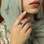 'Yusr' (Ease) Arabic calligraphy signet ring in 18k gold-plated sterling silver, worn on a finger to showcase the engraved face.