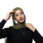 Model wearing the gold-plated sterling silver 'My Sister' Arabic calligraphy necklace (Ukhti) against a neutral background, showcasing its delicate chain and elegant script.