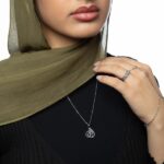 Model wearing the gold-plated sterling silver 'My Sister' Arabic calligraphy necklace (Ukhti) against a neutral background, showcasing its delicate chain and elegant script.