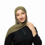 Model wearing the gold-plated sterling silver 'My Sister' Arabic calligraphy necklace (Ukhti) against a neutral background, showcasing its delicate chain and elegant script.