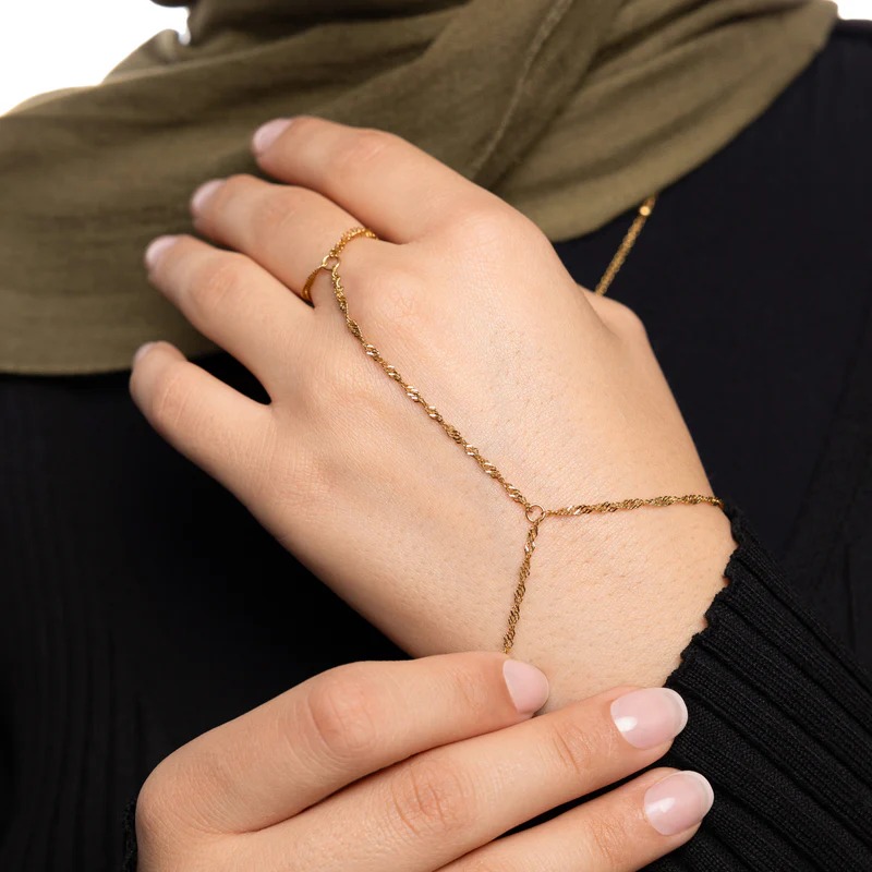 A woman's hand wearing the Twisted Rope Hand Chain in 18k gold-plated sterling silver, showing the delicate rope chain draping over the hand.