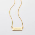 A vertical Shahada bar necklace in 18k gold-plated sterling silver, showing the clear Arabic calligraphy of the Islamic declaration of faith.