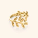 A delicate Olive Branch Peace Ring in 18k gold-plated sterling silver, worn on a finger to showcase the leaf design wrapping around it.