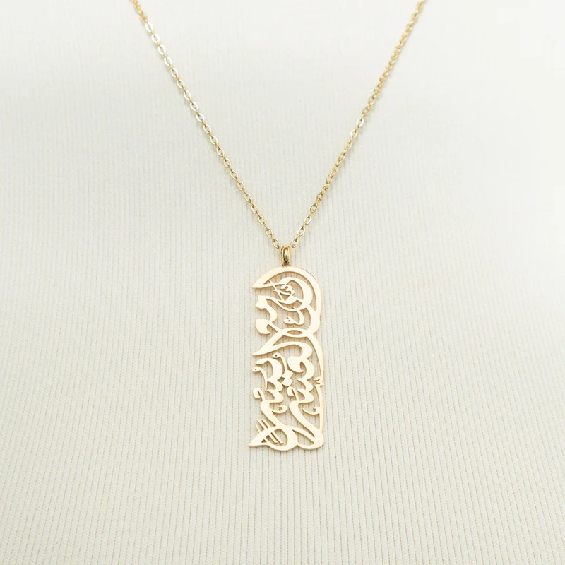 "With Hardship Comes Ease" medallion necklace in 18k gold-plated sterling silver, showcasing the intricate Arabic calligraphy engraving.