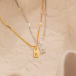 Signature initial 'K' tag necklace in 18k gold-plated sterling silver, hanging from a delicate chain against a neutral background.